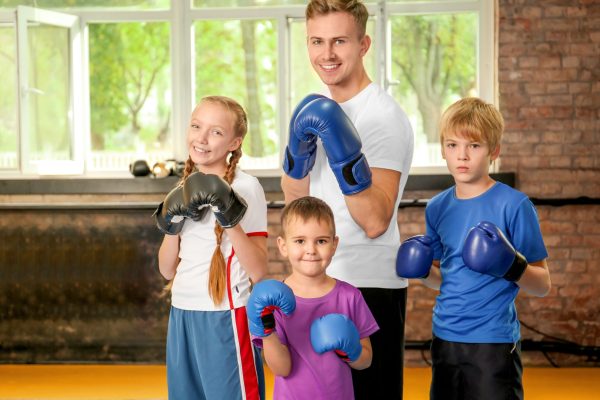 Little children in boxing gloves with trainer indoors
